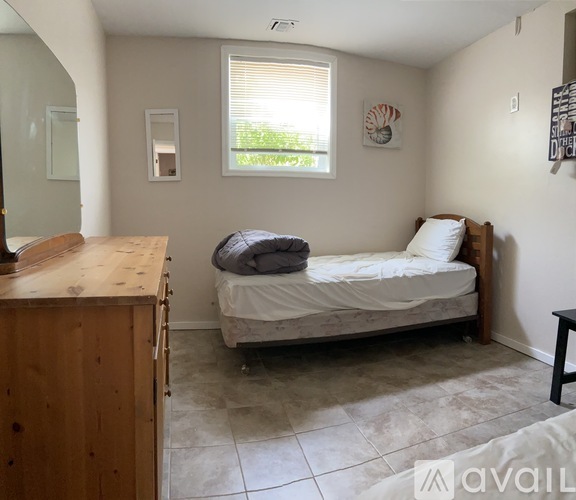 A bedroom with a bed, dresser, and window.