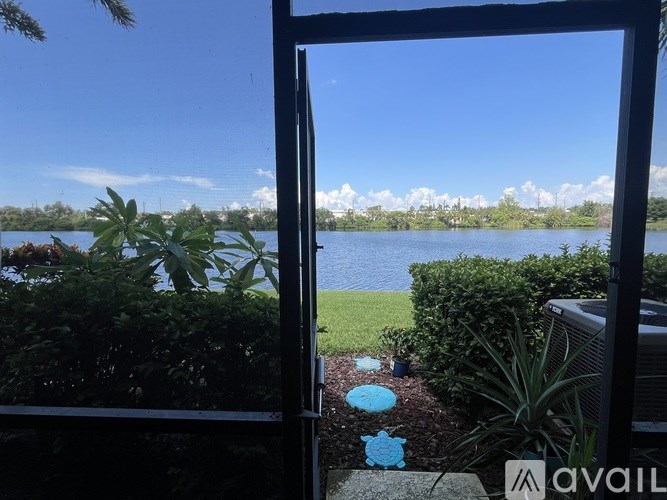 A view of a lake through a window with a blue flower on the ground.