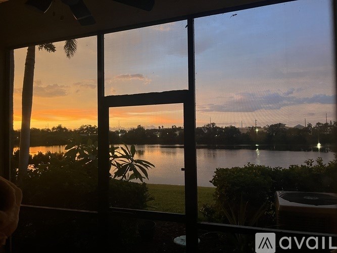 A view of a lake through a window with a sunset in the background.