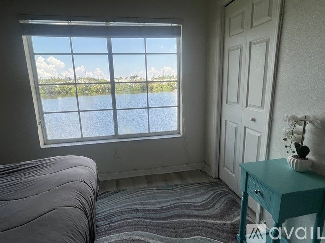 A room with a bed, a desk, and a window overlooking a body of water.