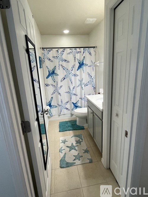 A bathroom with a toilet, sink, and shower curtain.