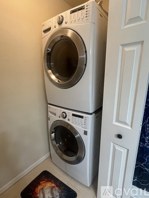 A white washing machine and dryer stacked on top of each other in a laundry room.