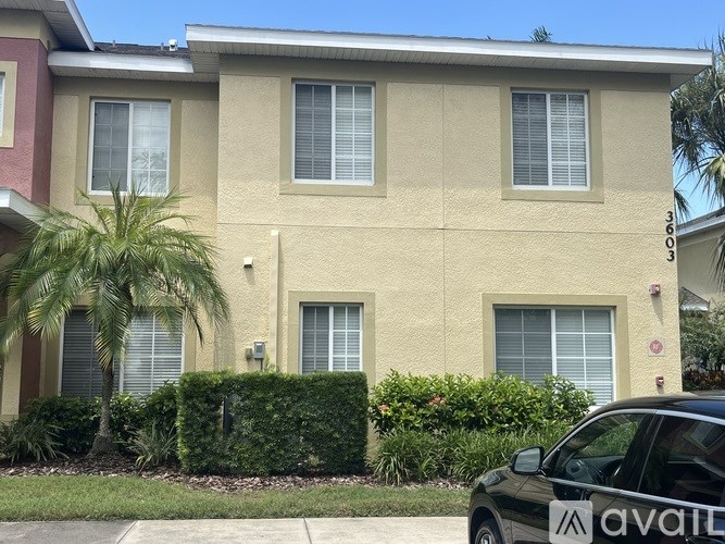 A black car with the word AVAILABLE on the side is parked in front of a beige house.