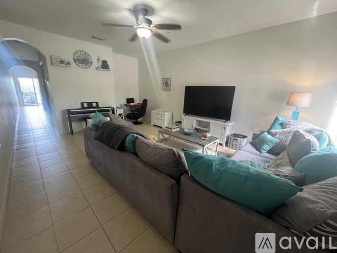 A living room with a couch, a television, and a fan.
