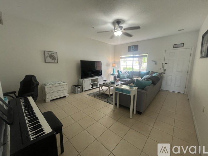 A living room with a piano, a couch, and a television.