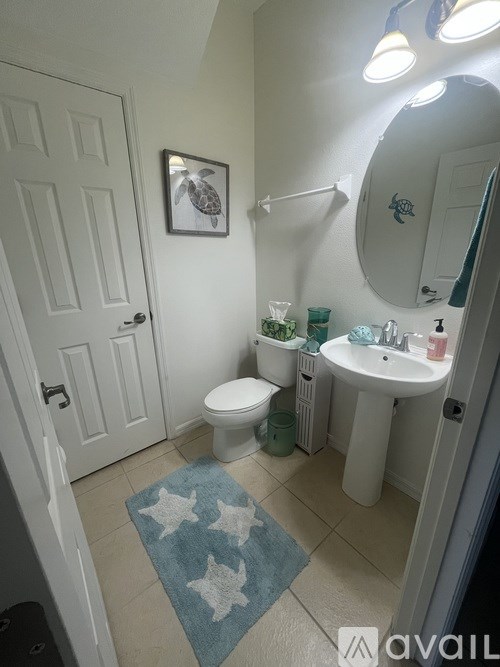 A bathroom with a white toilet, a white sink, and a blue rug with white stars.