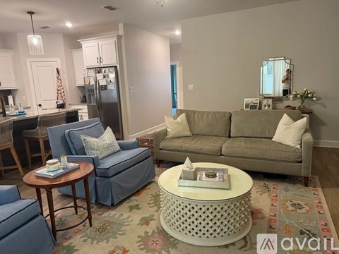 A living room with a grey couch, a blue chair, and a coffee table with a tissue box on it.