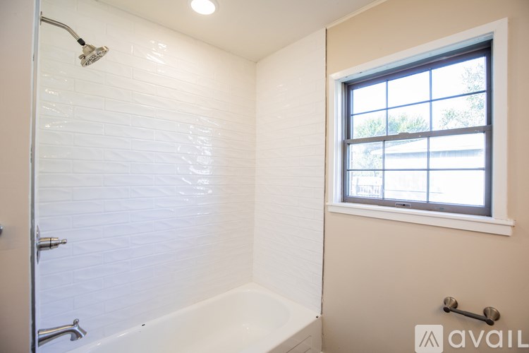 A white bathroom with a window and a bathtub.