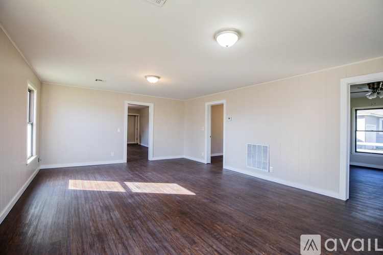 A spacious room with wooden floors and white walls.