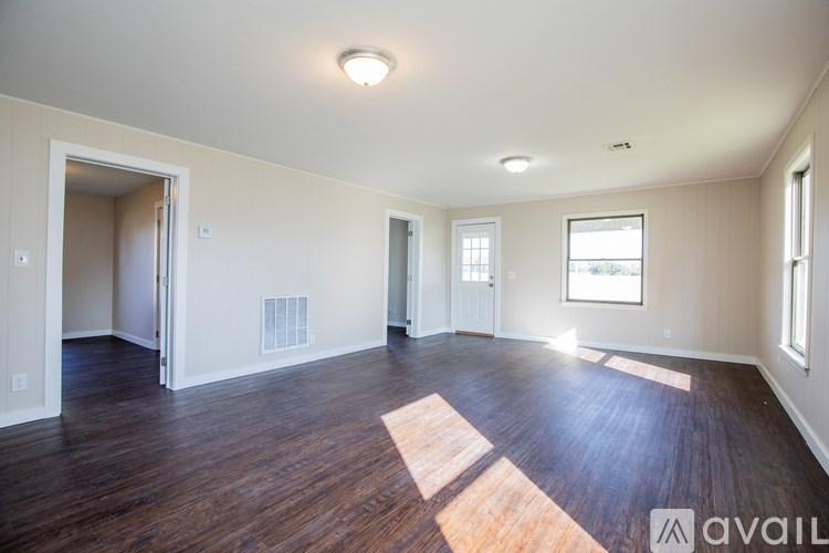 A spacious room with wooden floors and white walls.