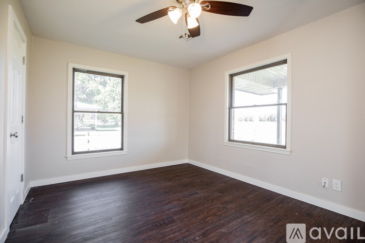 A room with a ceiling fan and two windows.