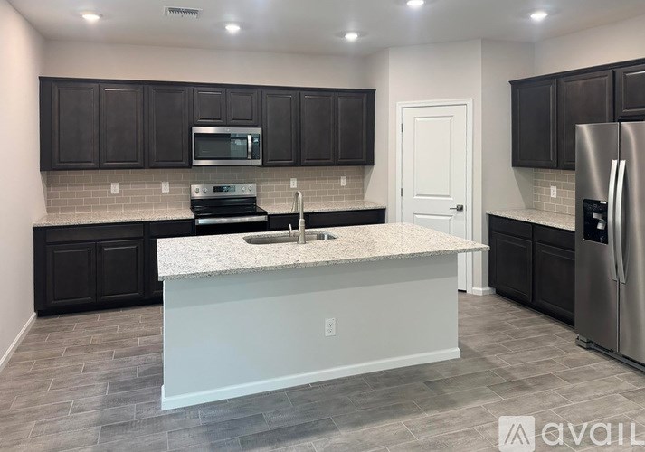 A kitchen with a white island and black cabinets.