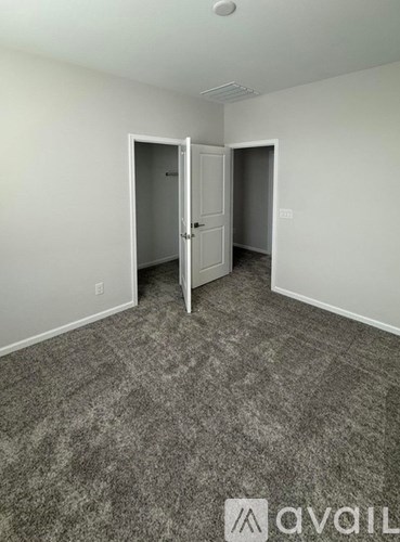 A carpeted room with two doors, one of which is open.