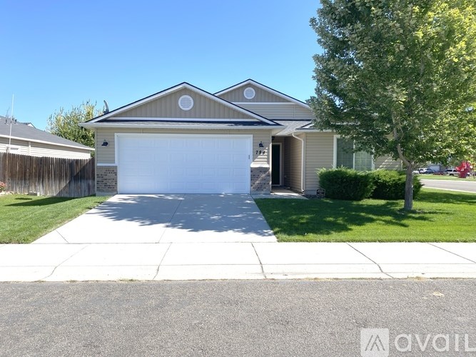 A house with a garage and a tree in front.