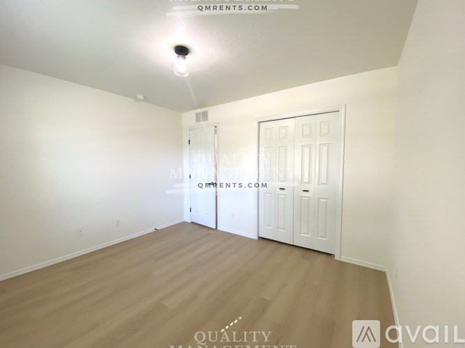 A room with a door and a window, with the text "QM RENTS.COM" and "QUALITY" on the wall.