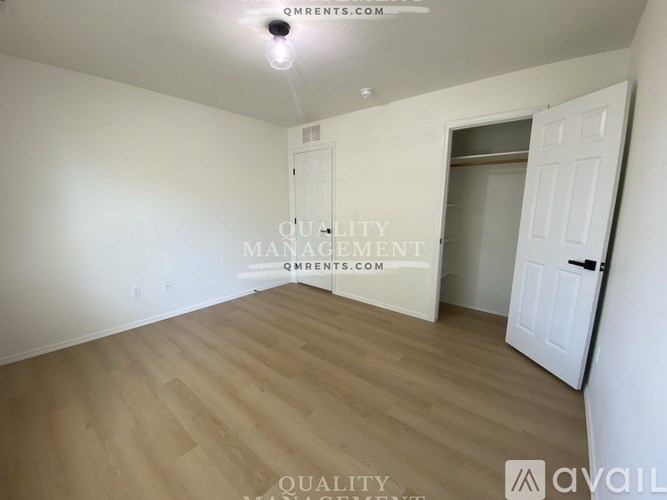 A room with wooden flooring and two doors, one of which is open.