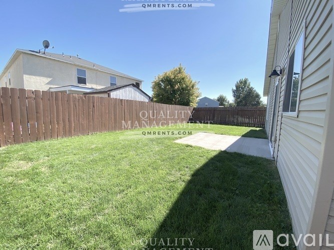 A backyard with a wooden fence and a white house.