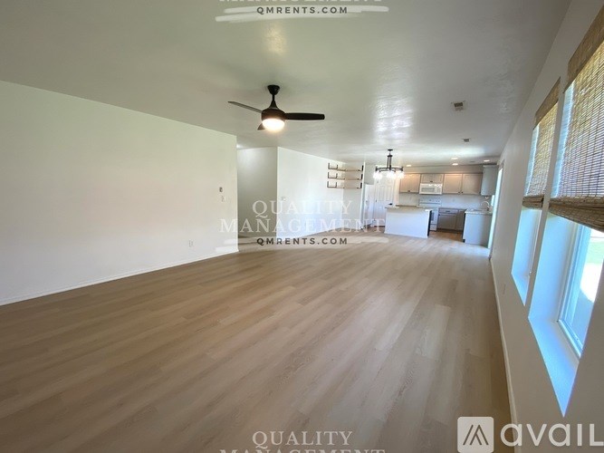 A spacious room with wooden flooring and a ceiling fan.