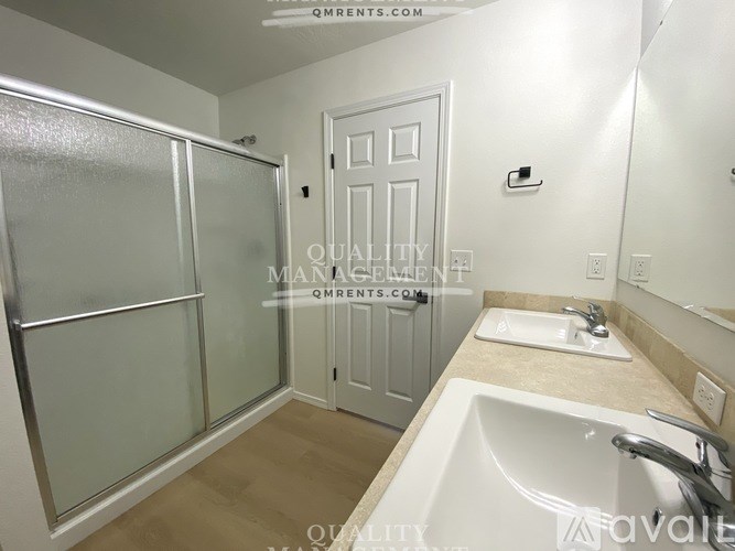 A bathroom with a sink, mirror, and shower.