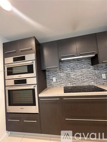 A modern kitchen with dark brown cabinets and stainless steel appliances.
