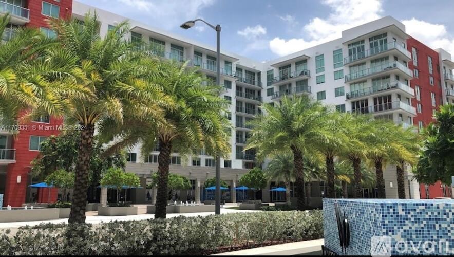 A modern apartment complex with palm trees in front.