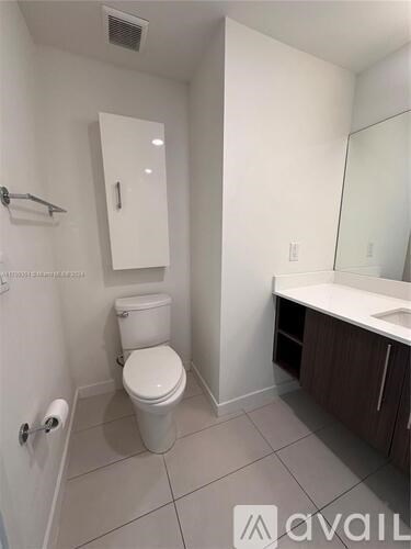 A white toilet in a small bathroom with a white cabinet and a white sink.