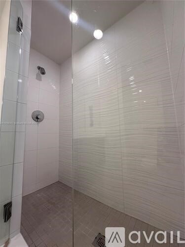A bathroom with a glass shower stall and a tiled floor.