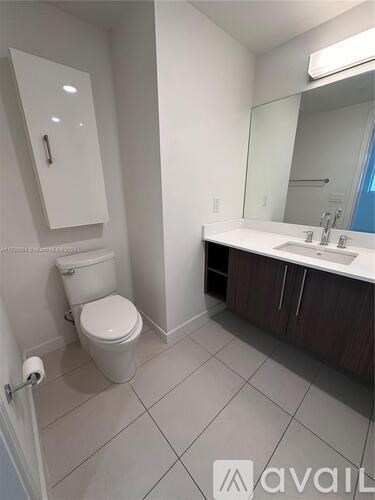 A white toilet sits in a bathroom with a white sink and a mirror.