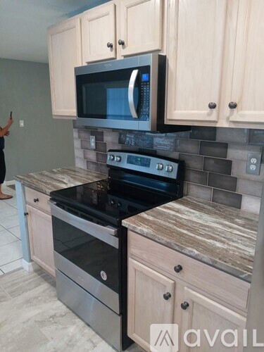 A kitchen with a black stove top oven and microwave above it.