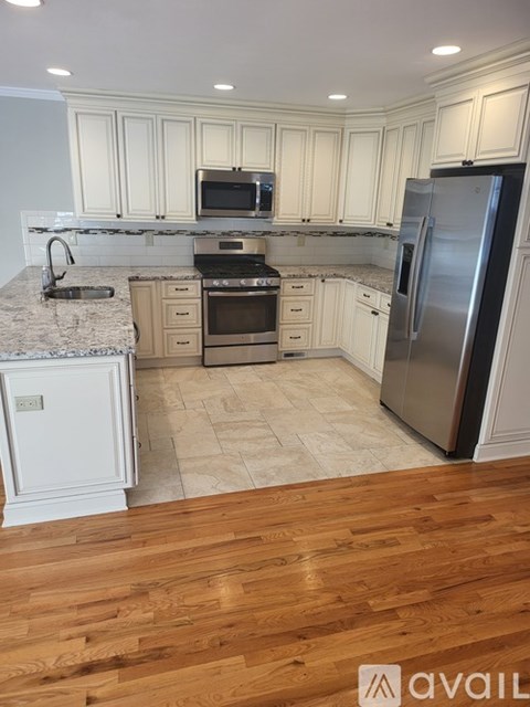 A kitchen with white cabinets and a wooden floor.