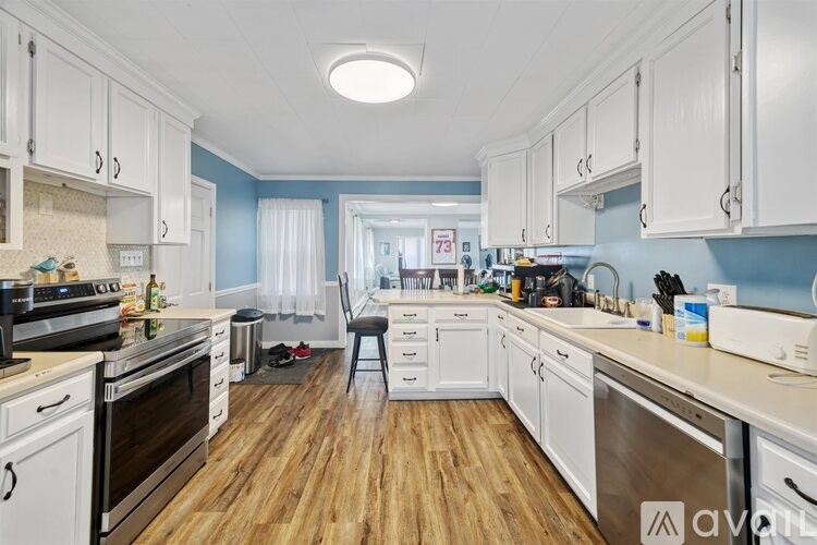 A kitchen with white cabinets and wooden floors.