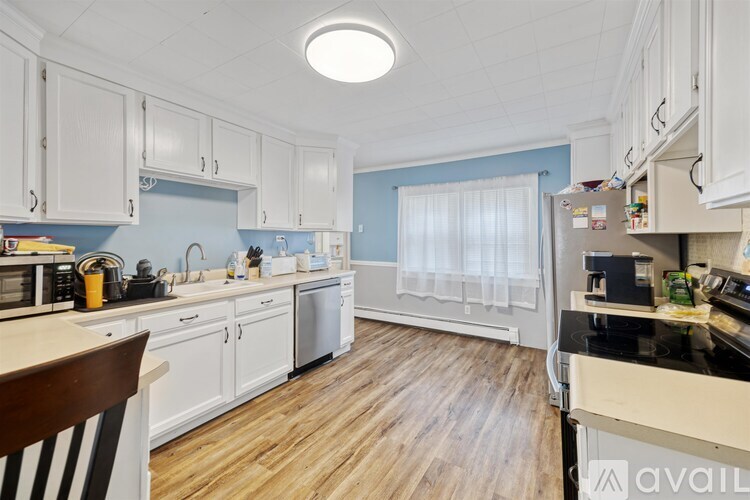A kitchen with white cabinets and wooden floors.