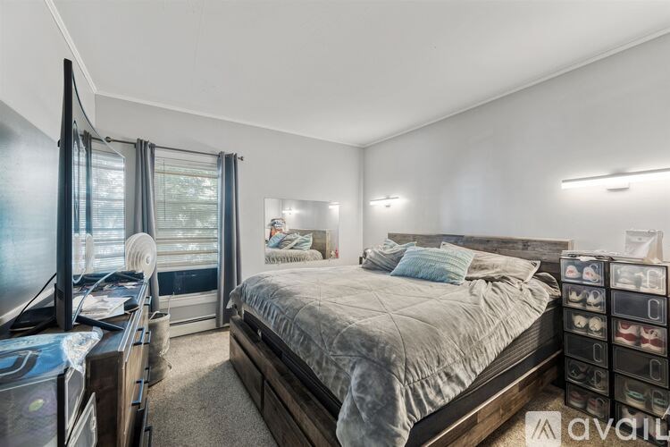 A bedroom with a large bed and a window with blinds.