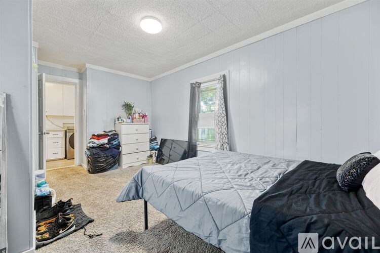 A bedroom with a bed, dresser, and window.