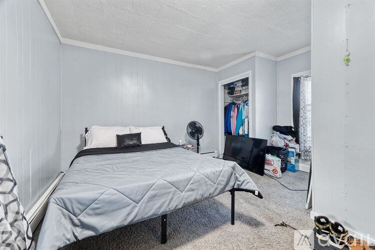 A bedroom with a bed, a fan, and a closet.