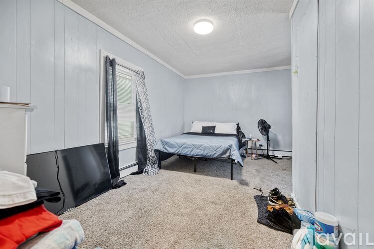 A bedroom with a bed, chair, and window.