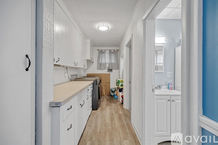A long hallway with white cabinets and a blue wall on the side.