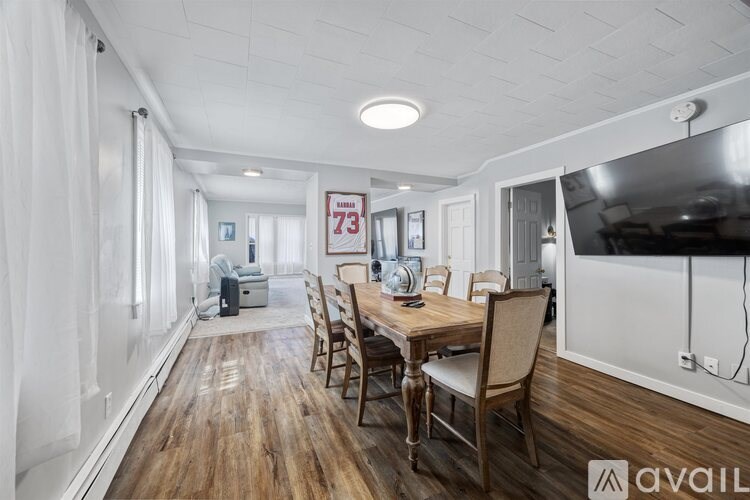 A room with a wooden table and chairs, a television, and a sign that reads "73" on the wall.