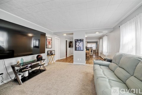 A living room with a grey couch and a black television.