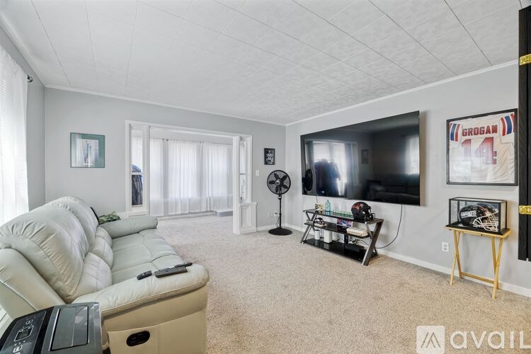 A living room with a white sofa and a flat screen TV mounted on the wall.