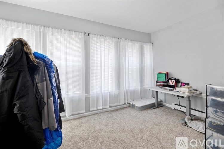 A person is standing in a room with a desk and a window with blinds.