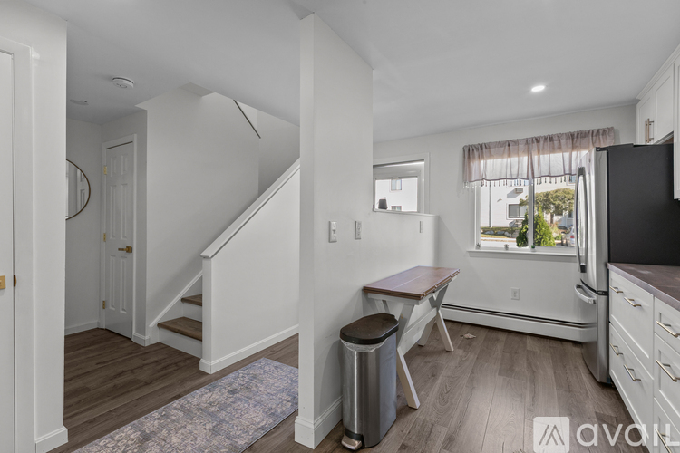 A kitchen with white walls and wooden floors.