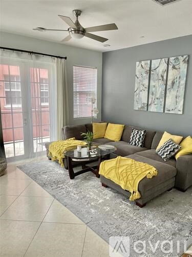 A living room with a grey couch and a yellow throw blanket.
