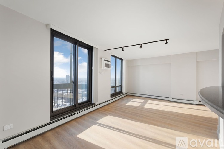 A spacious room with wooden flooring and large windows overlooking a cityscape.