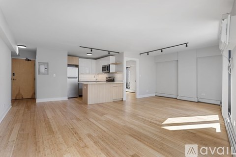 A spacious room with wooden flooring and white walls.