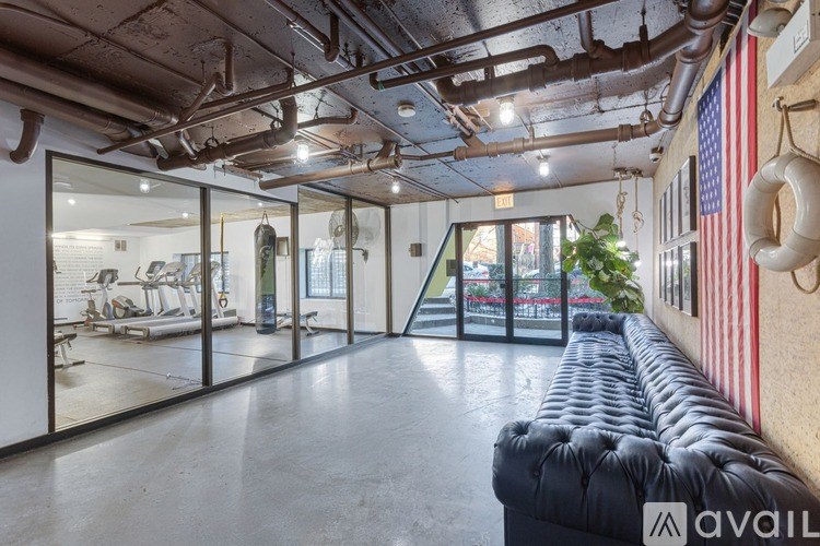 A spacious room with a black couch, a mirror, and a wall with a lifebuoy hanging on it.