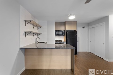 A kitchen with a black refrigerator and wooden floors.