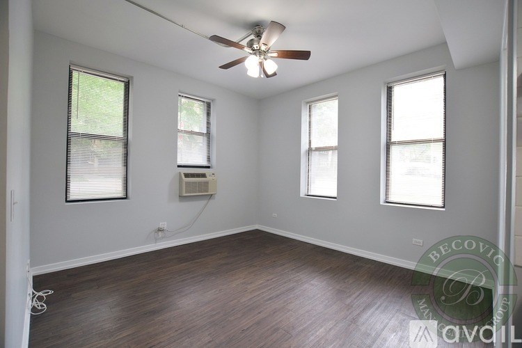 A room with a ceiling fan and three windows.
