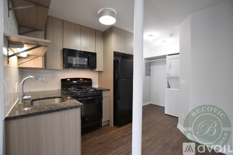 A kitchen with a black refrigerator and stove top oven.