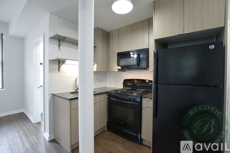 A kitchen with a black fridge and stove top oven.